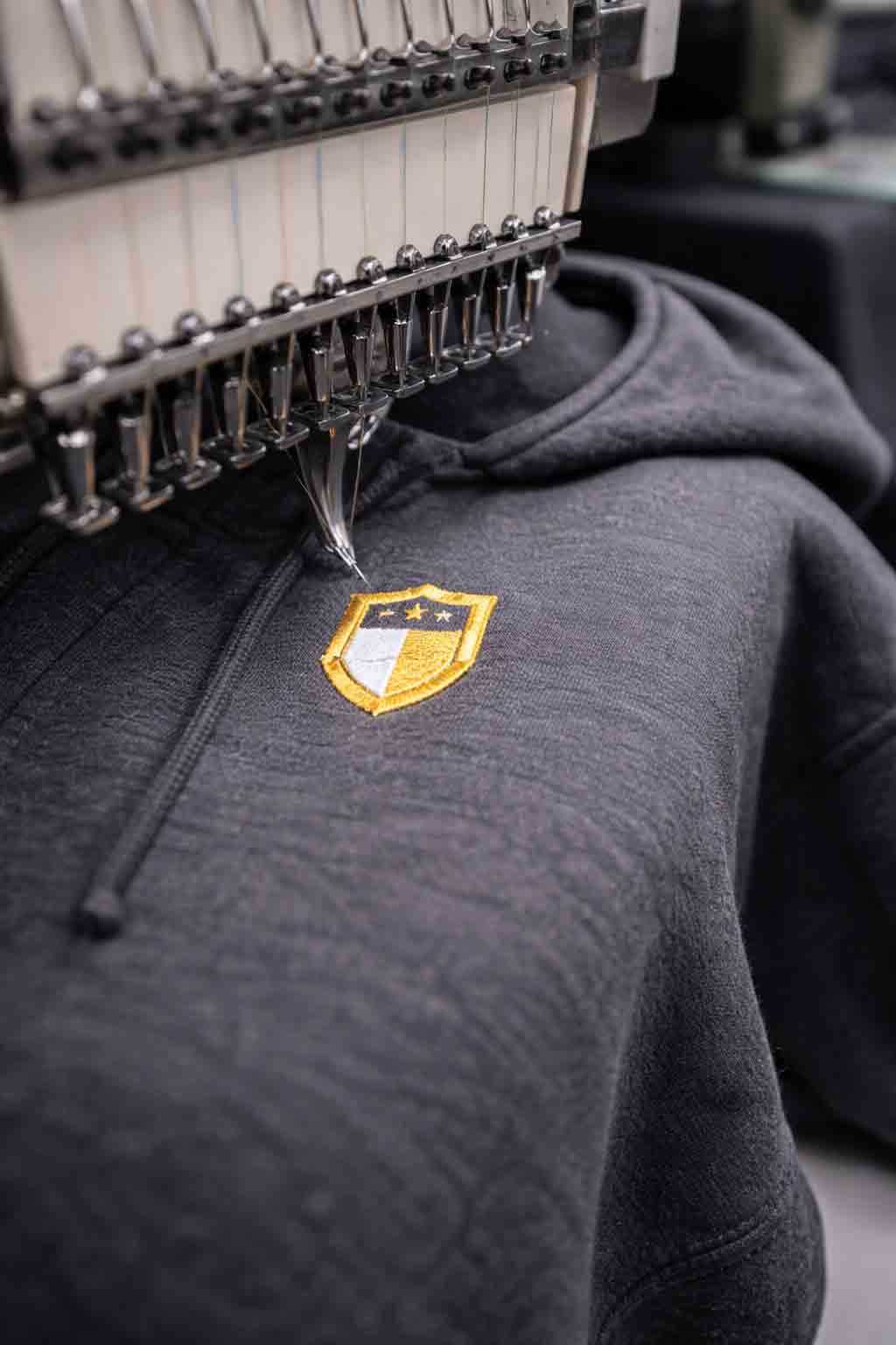 Portrait close-up of embroidery needle stitching on a hoodie with premium texture